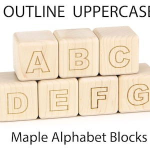 May include: Seven light-colored wooden blocks arranged in two rows, featuring the engraved outline letters A, B, C on the top row and D, E, F, G on the bottom row. The text OUTLINE UPPERCASE and Maple Alphabet Blocks appear in the image.