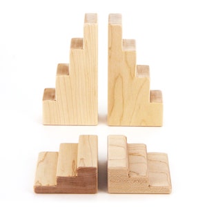 May include: Two sets of wooden bookends shaped like stairs. Each set has five steps and is made of light brown wood.