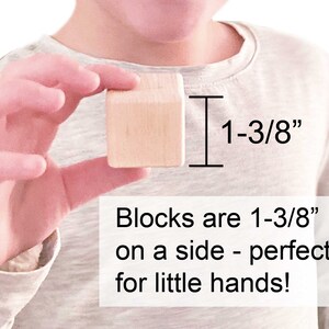 May include: A light-colored wooden cube block measuring 1-3/8 inches on each side. The image includes text stating: Blocks are 1-3/8 inches on a side - perfect for little hands! The block has a smooth, unfinished surface with visible wood grain.