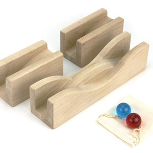 May include: A wooden marble run set with three wooden track pieces and two glass marbles. The track pieces are light-colored and have grooves for the marbles to roll through. The marbles are blue and red.