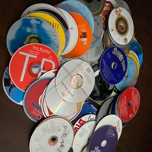 May include: A pile of various CDs with different artists and album titles. The CDs are arranged in a random order and some are stacked on top of each other. The CDs are all in good condition and have no scratches or damage.