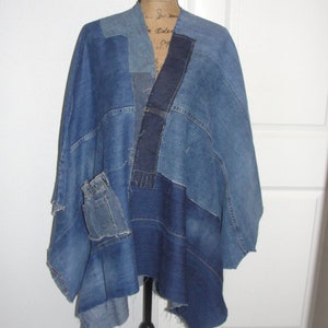 May include: A denim poncho made from recycled denim fabric. The poncho is blue and has a patchwork design. It has a pocket on the front and is asymmetrical in shape.