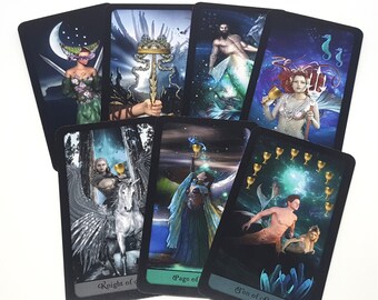 May include: A collection of tarot cards featuring fantasy art. The cards display images of mermaids, knights, and other mystical figures. The cards have a black border and are arranged on a white surface.