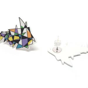 May include: A pair of geometric stud earrings with a colorful abstract design. The earrings are made of white acrylic and feature a silver post.