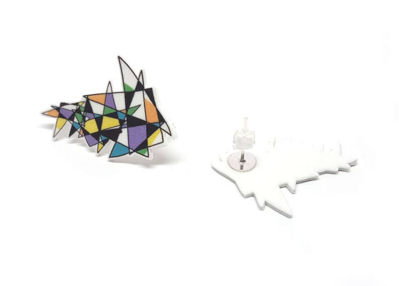 May include: A pair of geometric stud earrings with a colorful abstract design. The earrings are made of white acrylic and feature a silver post.