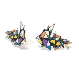 May include: A pair of colorful geometric earrings with a black outline. The earrings are made of acrylic and have a modern, abstract design.