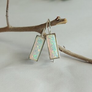 Peut inclure: Une paire de boucles d'oreilles pendantes en argent avec des pierres d'opale blanches rectangulaires.
