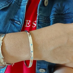 May include: A silver bangle bracelet with a hammered finish and small turquoise stones set into the metal.