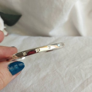 May include: A silver bangle bracelet with small clear stones set around the band.
