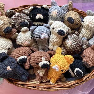 Puede incluir: Una cesta de mimbre llena de peluches de animales de crochet. Los peluches son de varios colores, incluyendo marrón, blanco, negro, gris y amarillo. Los peluches son todos animales diferentes, incluyendo perros, gatos y osos.