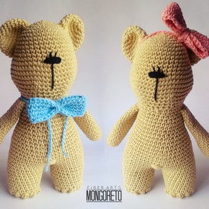 May include: Two crocheted teddy bears, one with a blue bow tie and the other with a pink bow. Both bears have black eyes and are made with beige yarn.