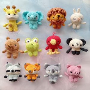 Puede incluir: Una colección de doce juguetes de animales de ganchillo hechos a mano, incluyendo una jirafa, un elefante, un león, un conejo, un oso, una rana, un pájaro, un panda, un mapache, un zorro, un koala y un cerdo. Cada juguete está hecho con hilo colorido.