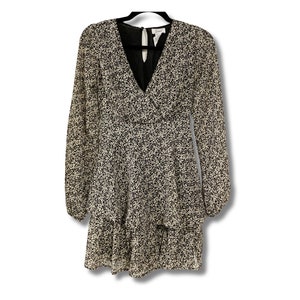 May include: A white and black patterned dress with a V-neckline and long sleeves. The dress has a ruffled hem and a black lining.