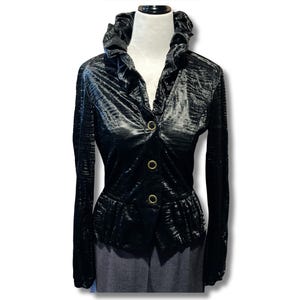 May include: Black velvet jacket with a ruffled collar and gold-coloured buttons. The long-sleeved jacket has a fitted waist and a textured, ribbed pattern. The jacket is displayed on a mannequin.