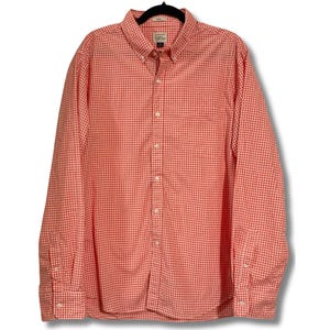 Puede incluir: Una camisa de manga larga con botones y un estampado de cuadros rojos y blancos.