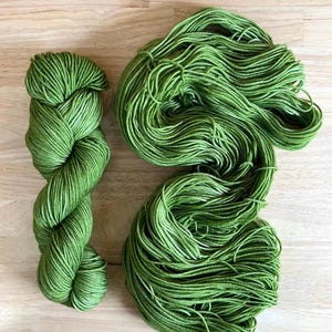 May include: Two skeins of green yarn, one skein is twisted into a figure eight shape, the other skein is in a loose ball.