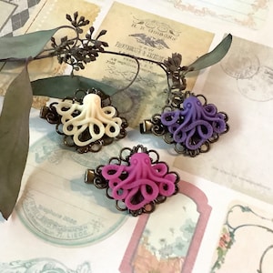 May include: Three octopus hair clips with ornate metal frames. The octopus is made of polymer clay and comes in white, purple, and pink.