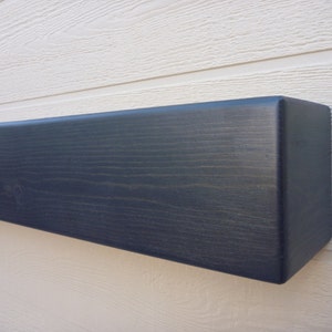May include: A dark gray wooden shelf with a slightly rounded edge. The shelf is made of solid wood and has a natural wood grain.