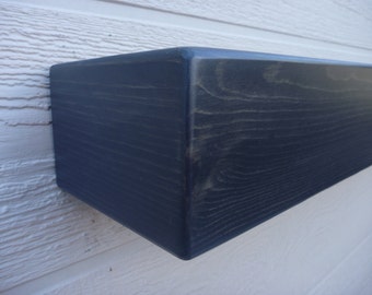 May include: A dark blue wooden shelf with a smooth, painted finish. The shelf is mounted on a white wall.