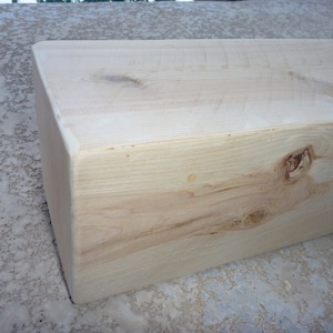 May include: A close-up of a light brown wooden beam with a knot in the center. The beam is smooth and has a natural finish.