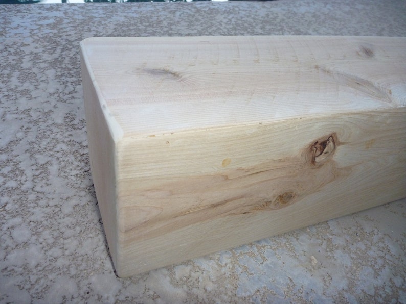 May include: A close-up of a light brown wooden beam with a knot in the center. The beam is smooth and has a natural finish.