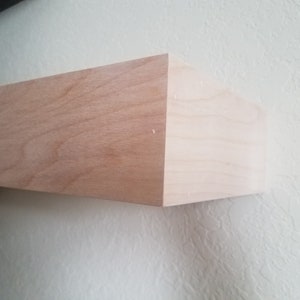 May include: A light wood shelf with a smooth, natural finish. The shelf is mounted to a white wall.