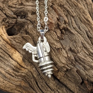 May include: A silver necklace with a detailed pendant shaped like a small, winged rocket ship.