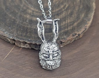 May include: A silver-toned metal pendant shaped like a rabbit head with long, textured ears and a menacing facial expression, suspended from a matching silver-toned link chain. The pendant features intricate detailing on the face and ears.