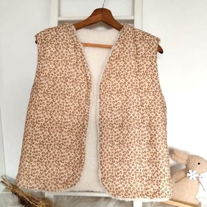 May include: A sleeveless vest with a brown and white leopard print pattern. The vest is lined with white faux fur.