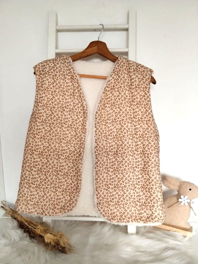 May include: A sleeveless vest with a brown and white leopard print pattern. The vest is lined with white faux fur.