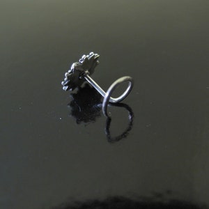 May include: Silver nose ring with a decorative flower design.