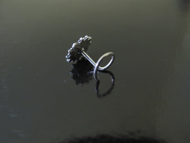May include: Silver nose ring with a decorative flower design.