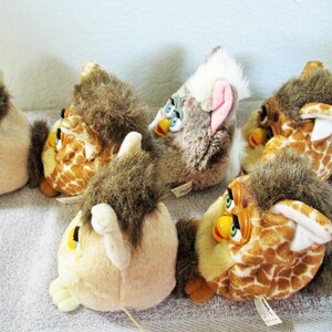 May include: A group of vintage plush toys, each with a unique design. The toys feature a variety of colours, including brown, tan, and white. The toys have large eyes and a distinctive, bird-like appearance. The toys are arranged on a light-coloured surface.