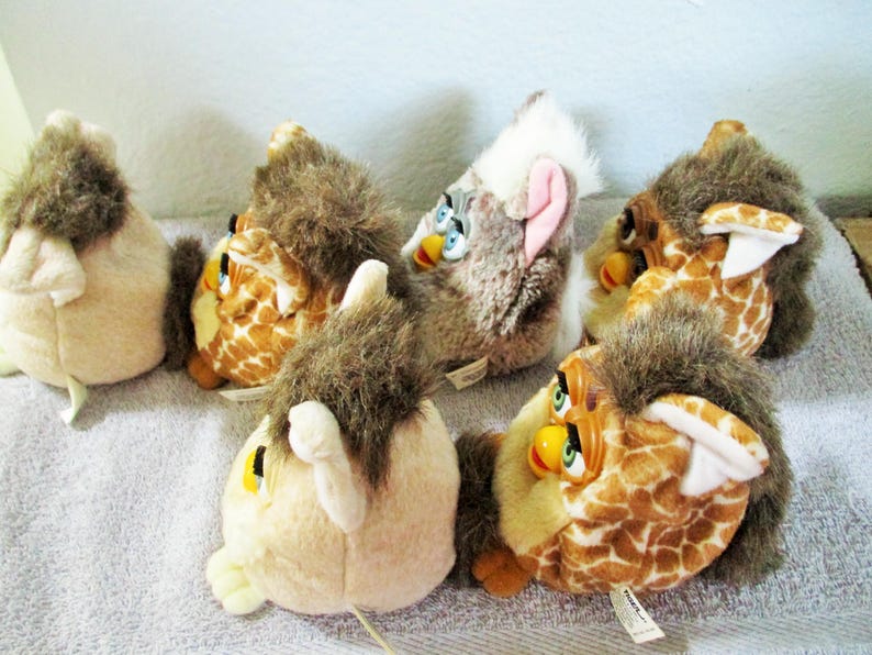 May include: A group of vintage plush toys, each with a unique design. The toys feature a variety of colours, including brown, tan, and white. The toys have large eyes and a distinctive, bird-like appearance. The toys are arranged on a light-coloured surface.