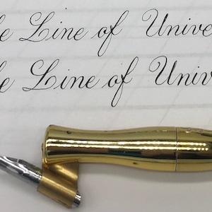 May include: Close-up of a calligraphy pen with a gold-colored barrel and a silver nib. The pen is positioned near handwritten text that reads "The Line of Universal". The script is in elegant cursive.