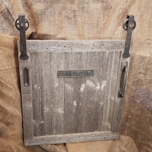 May include: A rustic wooden door with a metal handle and a sign that reads "Wine Cellar". The door is on a burlap background.