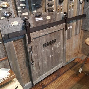 May include: A rustic wooden door with a metal handle and a sliding barn door track. The door is labeled "Wine Cellar".