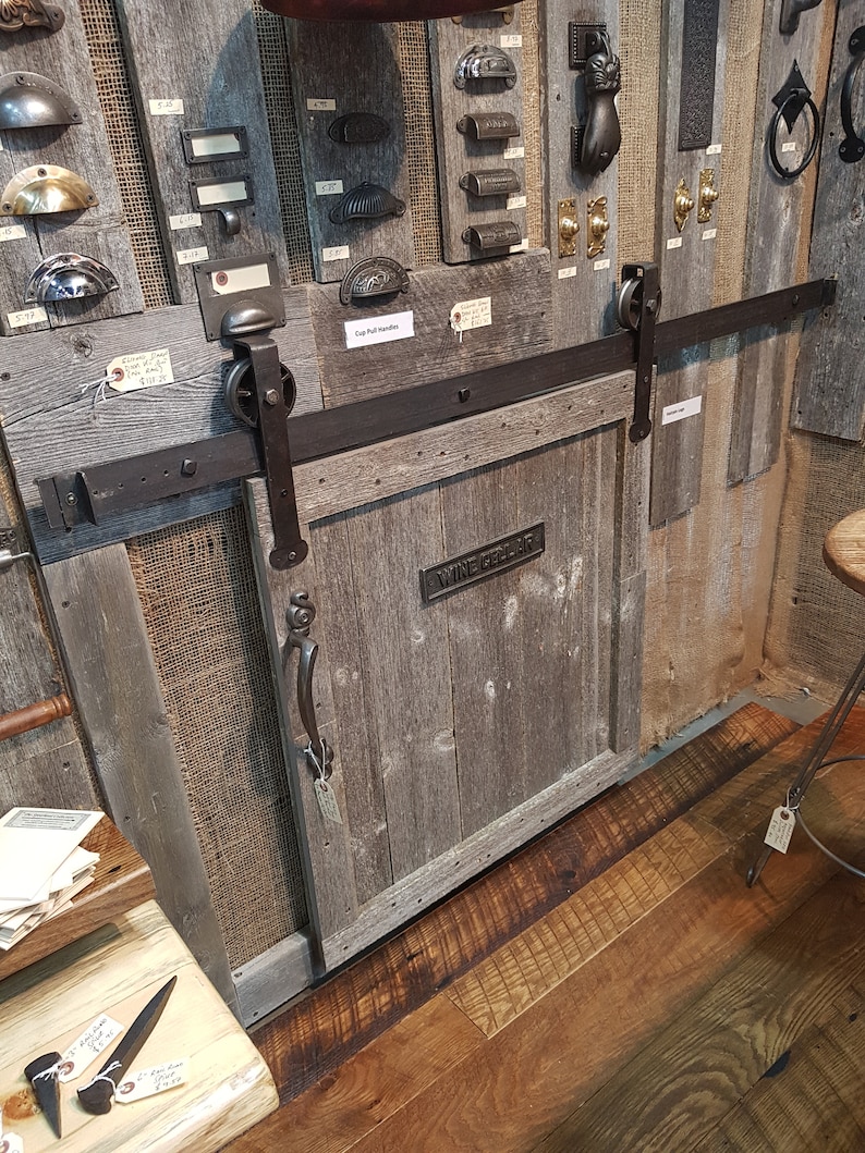 May include: A rustic wooden door with a metal handle and a sliding barn door track. The door is labeled "Wine Cellar".