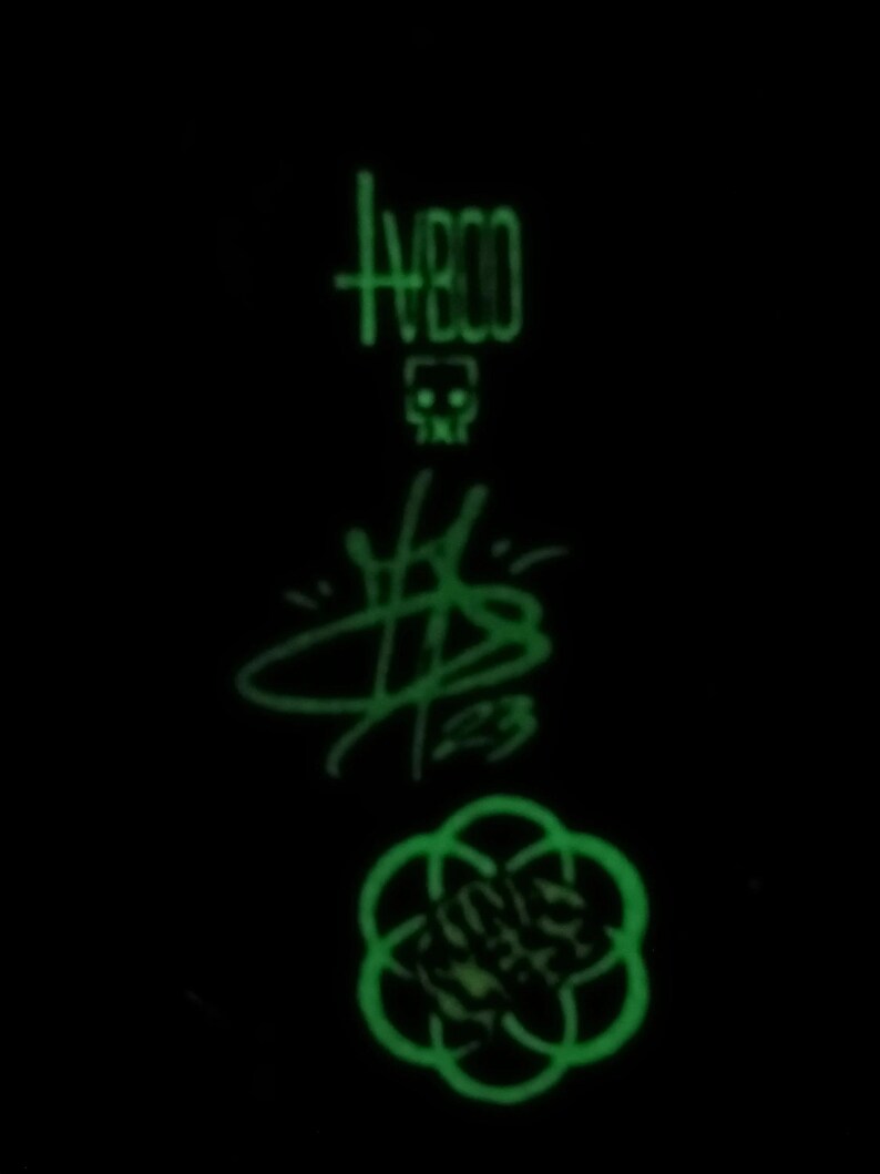 May include: A green glow-in-the-dark sticker with a skull, the word "HBO", a stylized "$B", and a circular design.