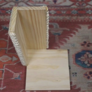 Op de afbeelding: Een houten hoekplank met een touwrand. De plank is gemaakt van licht hout en heeft een eenvoudig ontwerp.