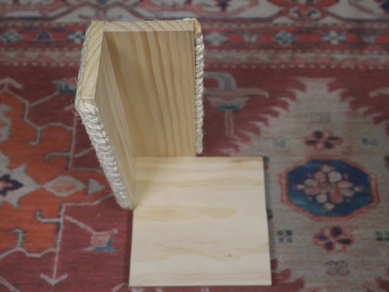 Op de afbeelding: Een houten hoekplank met een touwrand. De plank is gemaakt van licht hout en heeft een eenvoudig ontwerp.