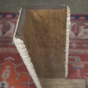 Op de afbeelding: Een houten plank met een witte touwrand. De plank is gemaakt van natuurlijk hout en heeft een rustieke uitstraling.