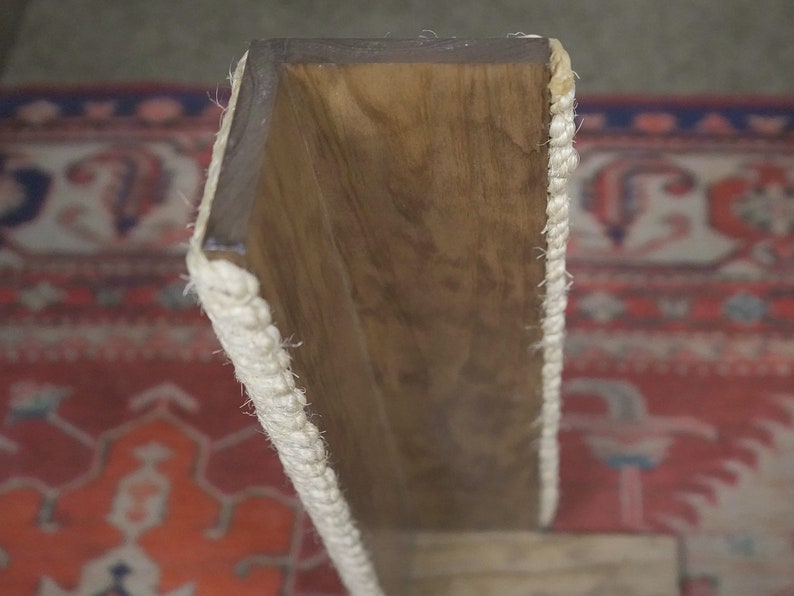 Op de afbeelding: Een houten plank met een witte touwrand. De plank is gemaakt van natuurlijk hout en heeft een rustieke uitstraling.