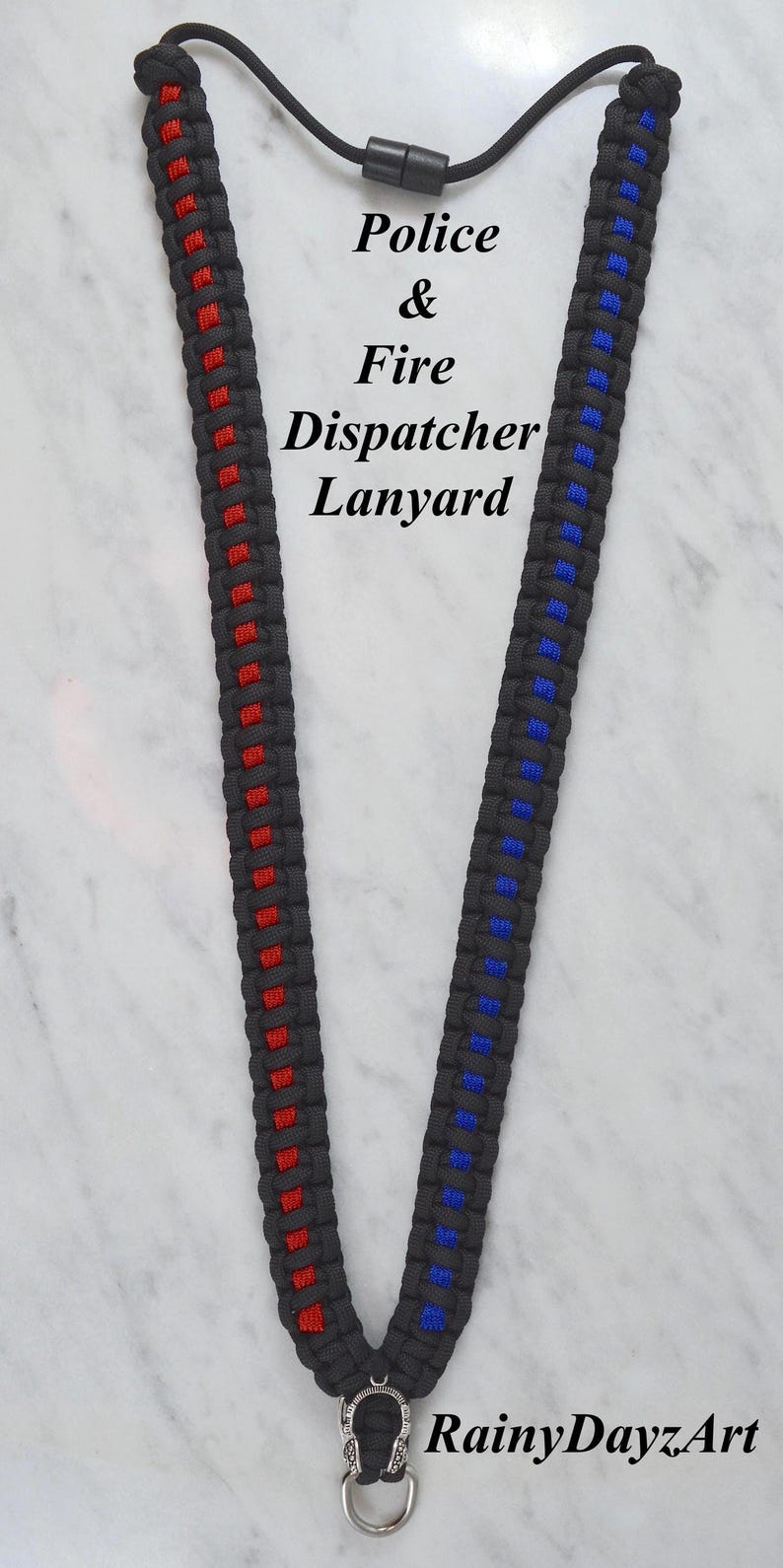 May include: Black lanyard with red and blue accents, featuring the text "Police & Fire Dispatcher Lanyard." The lanyard has a metal clasp and a black cord. The RainyDayzArt logo is visible.