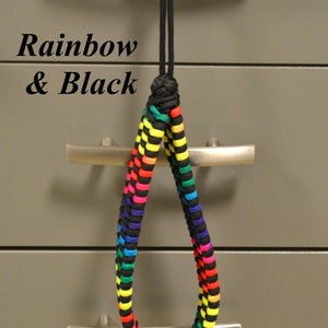 May include: A rainbow and black paracord lanyard with a knot at the top. The lanyard is hanging from a silver handle on a metal drawer.