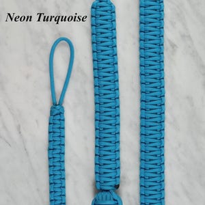 May include: Three neon turquoise paracord lanyards with woven patterns and spherical knots at the ends. The items are labeled Small, Large, and Extra Large. The text RainyDayzArt and Neon Turquoise are visible on the image, showcasing the design.