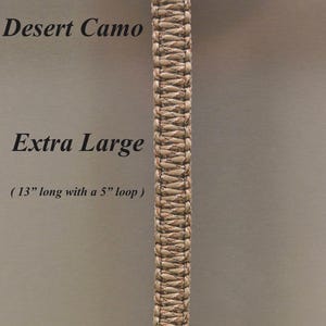 May include: A desert camo paracord lanyard featuring a braided design with a knot at the bottom and a loop at the top. The text reads Desert Camo, Extra Large, 13 inches long with a 5 inch loop, and RainyDayzArt. The lanyard is hanging vertically.