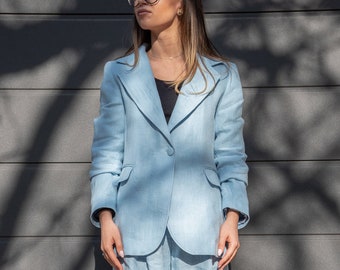 May include: A light blue linen suit with a blazer and wide-leg pants. The person is wearing black shoes and glasses.