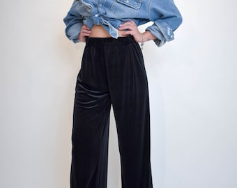 May include: A woman wearing black velvet wide-leg pants with a denim shirt tied at the waist.