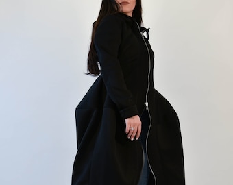 May include: A black long-sleeved hooded jacket with a zipper closure and a gathered skirt-like hem. The jacket is worn with blue jeans and black heeled boots.